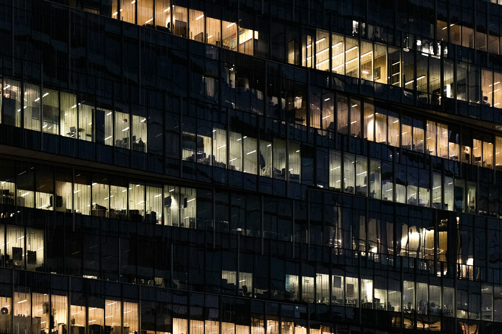 Night view of a multi-story glass curtain wall with office lights on behind the grid