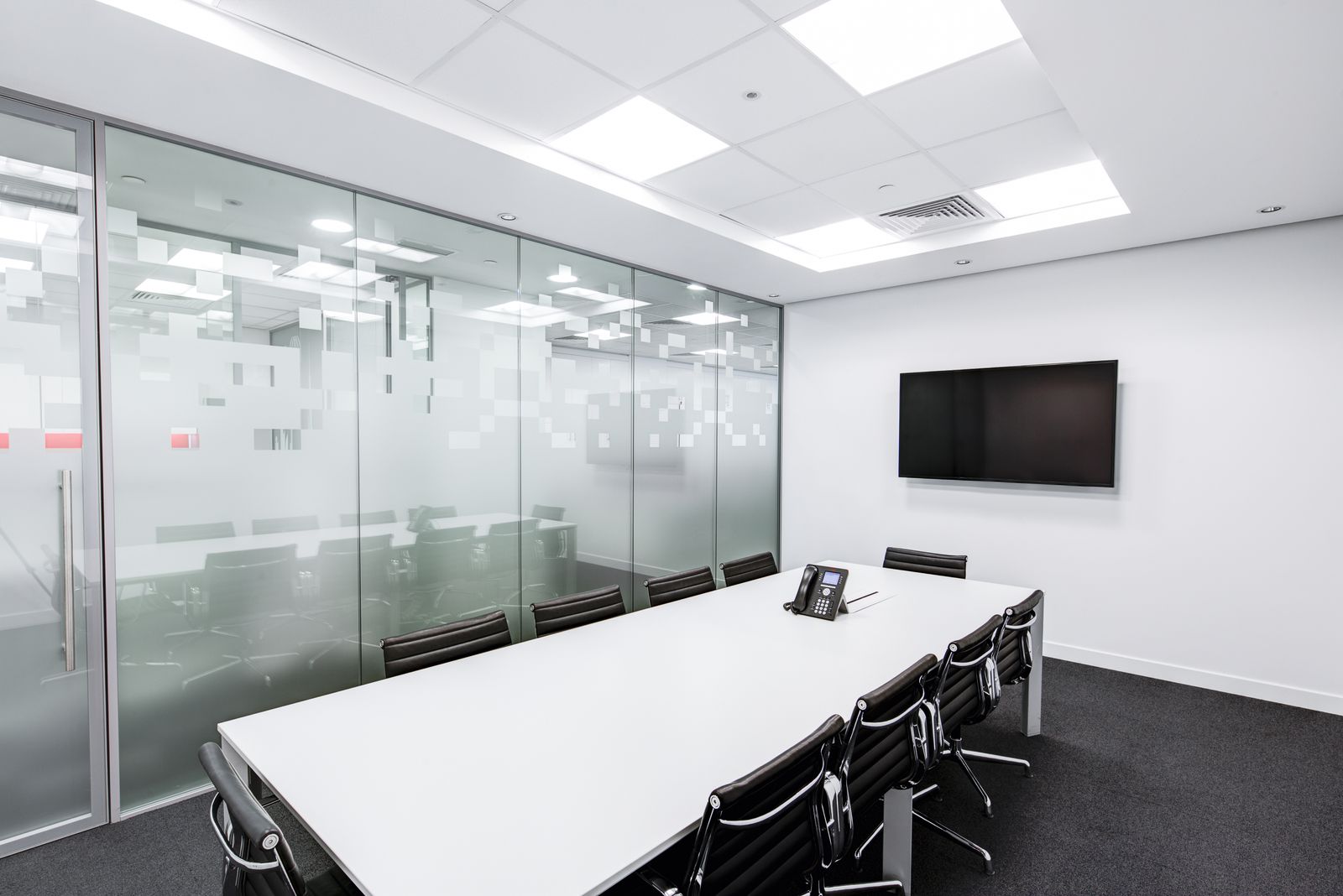 Interior commercial conference room with floor-to-ceiling glass partitions and a glass door