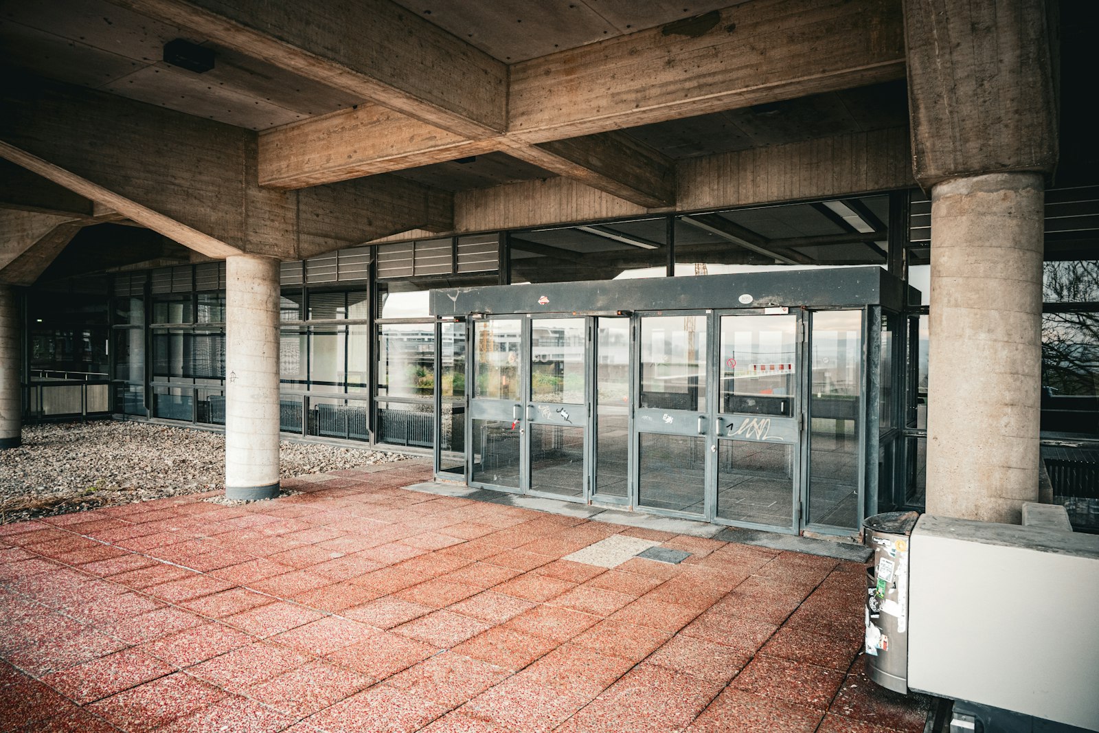 Automatic sliding glass entrance set in a dark-framed vestibule under a concrete canopy